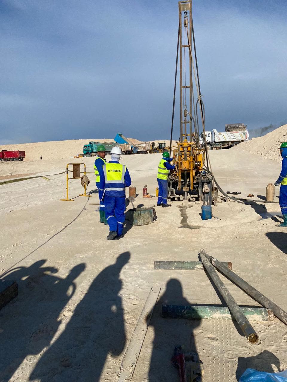 Horema crew and drilling rig mobilised on a large earthworks site with haul trucks working in the background